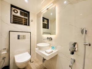 a white bathroom with a toilet and a sink at Hotel Eastern Dham Puri in Puri