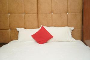a red pillow sitting on top of two white pillows on a bed at Hotel Nova in Itahari
