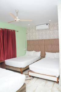 three beds in a room with a red curtain at Hotel Nova in Itahari