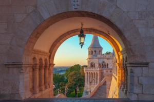 a view through an arch of a building with a tower at BEM MINI STUDiO in Budapest