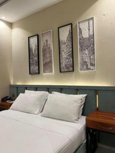 a bedroom with a bed with four pictures on the wall at Shelton Boulevard Hotel Lahore in Lahore