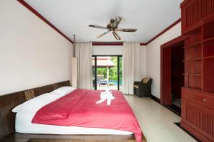 a bedroom with a bed with a red blanket and a ceiling fan at The Baan Bua Elefant Villa in Rawai Beach +37 photos