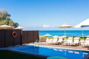 レティムノ・タウンにあるIris Luxury Beach Front Residence, By ThinkVillaの海のそばのスイミングプール(椅子、パラソル付)