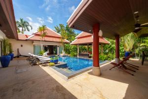 a backyard with a swimming pool and a house at The Baan Bua Elefant Villa in Rawai Beach