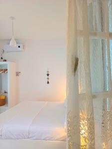 a white bedroom with a bed and a window at Georgia Rooms Milos in Plaka Milou