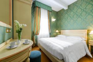 a bedroom with a bed and a desk with cups and saucers at Hotel Villa Delle Palme in Venice-Lido