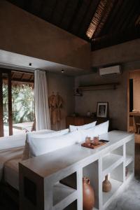 a bedroom with a white bed and a table at RONJA Boutique Hotel - Adults Only in Uluwatu