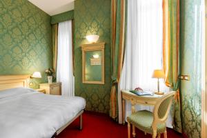 a bedroom with a bed and a table and a window at Hotel Villa Delle Palme in Venice-Lido