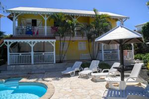 a house with a pool and chairs and a umbrella at L'escapade in Sainte-Anne