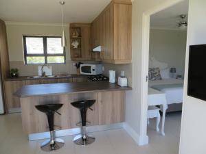 a kitchen with a counter and a bed in a room at Sunbird Cottage in Noordhoek