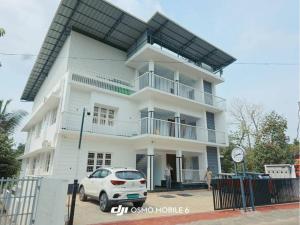 a white car parked in front of a white building at Science House Lux Inn in Kadayirippu