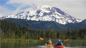 two people in kayaks on a lake with a snow covered mountain at Anissa Shasta Hostel in Weed