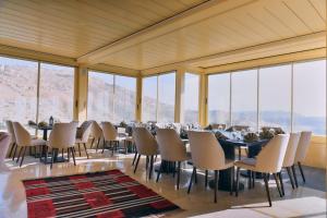 a dining room with tables and chairs and windows at Petra Moon Hotel in Wadi Musa