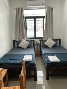 two twin beds in a room with a window at SDD HoSTEL in Thung Si Kan