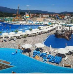 a large swimming pool with blue chairs and umbrellas at Apolon Spa in Vrnjačka Banja