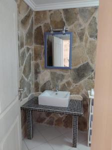 a bathroom with a sink and a mirror on a stone wall at Muo Suntime apartment in Muo +26 photos