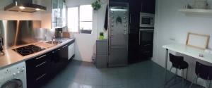 a kitchen with a stove and a sink and a refrigerator at Piso Playa Patacona/Malvarrosa in Valencia