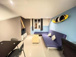 a living room with a purple couch and a surfboard on the wall at Cosytel in Bègles
