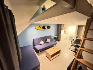 a living room with a purple couch and a surfboard on the wall at Cosytel in Bègles