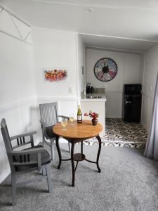 a dining room with a table and chairs and a clock at Little Eden in Matamata