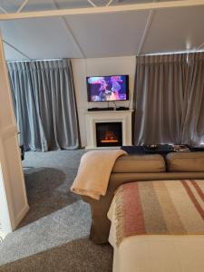 a bedroom with a fireplace and a tv and a couch at Little Eden in Matamata