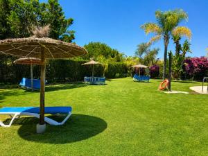 a park with chairs and umbrellas on the grass at Casa Denver in El Rompido