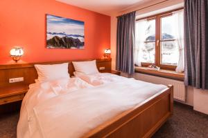 Schlafzimmer mit einem großen weißen Bett vor einem Fenster in der Unterkunft Alpenflair Ferienwohnungen Whg. 304+203 in Oberstdorf