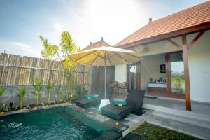 a pool with an umbrella next to a house at The Wise 1 Bedroom Private Pool Villa Ubud in Ubud
