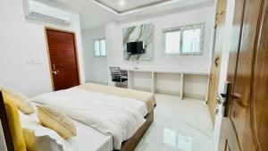 a white bedroom with a bed and a desk at Sai Sansthan Inn in Lucknow