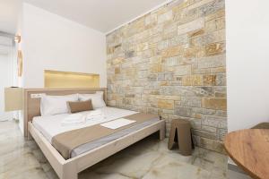 a bed in a room with a brick wall at VillAge 1912 Studios in Panagia
