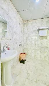 a white bathroom with a sink and a toilet at Sai Sansthan Inn in Lucknow