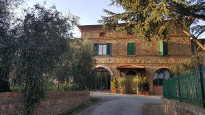 an old brick house with green shutters on a street at Orto degli Ulivi in Sinalunga