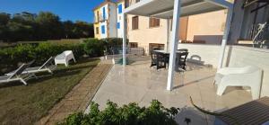 a patio with white chairs and a table on a building at La casa al mare, Pittulongu in Olbia