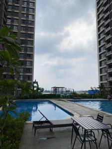 a swimming pool with two benches and two buildings at Sky House Hotel Style Bed IKEA 5min in Kampungklapa 2