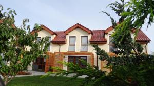 ein weißes Haus mit einem roten Dach in der Unterkunft Koralia Domki i Apartamenty Basen z podgrzewaną wodą in Sarbinowo