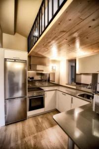 a large kitchen with stainless steel appliances and wooden ceilings at Apartamentos Áncora in Barro de Llanes