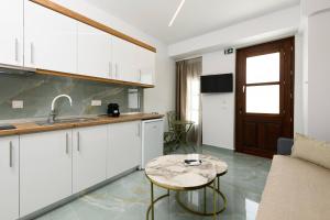a kitchen with white cabinets and a table in a room at VillAge 1912 Studios in Panagia +10 photos