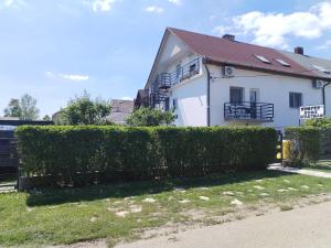 a white house with a hedge in front of it at Dömper Döme Apartman in Balatonlelle