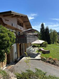 a building with a patio and an umbrella at Charmant appartement avec jardin et magnifique vue in Saint-Jean-de-Sixt
