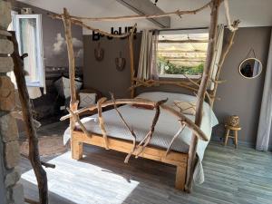 a bedroom with a bed made out of logs at Le petit cabanon in Lagorce