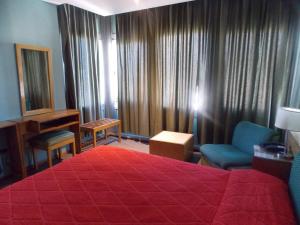 a hotel room with a red bed and a piano at Hotel cirse cr in Comodoro Rivadavia