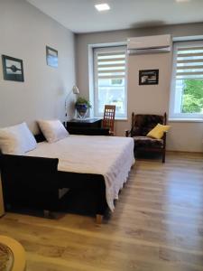 a bedroom with a large bed and a chair at Apartamentai Heydekrug in Šilutė