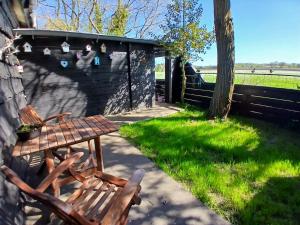 a wooden bench sitting in the grass next to a fence at 't Prentenhokkie in Stuifzand