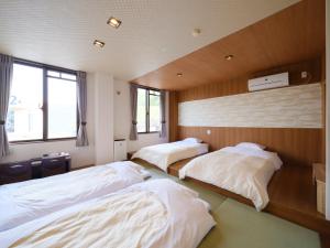 a room with three beds in it with windows at Isahaya Daiichi Hotel in Isahaya