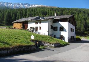 a white building on a hill with mountains in the background at Fuldera Daint chasa Zanoli Whg im zweiten Stock in Fuldera