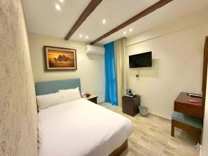 a bedroom with a white bed and a television at Pyramids Glory Inn in Cairo