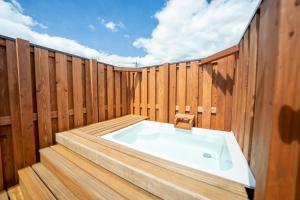 a jacuzzi tub in a wooden fence at raw 白馬唯一屋上露天を独り占めできるデザインコンテナホテル in Hakuba