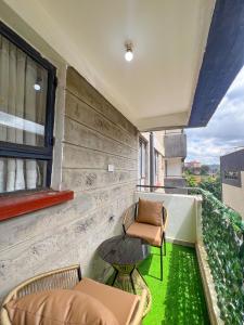 a balcony with chairs and a table and green grass at The Escape Muthiga Waiyaki way in Nairobi