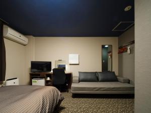 a bedroom with a bed and a couch and a desk at Isahaya Daiichi Hotel in Isahaya