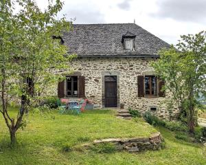 an old stone house with a grass yard at Chez Caro in Mourjou